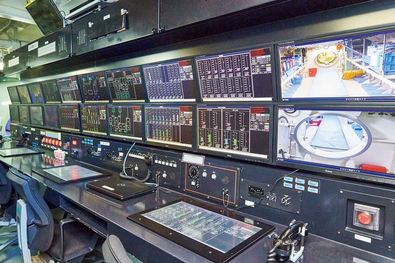 画像: 飽和潜水員が、飽和潜水の前に1週間ほど入る「飽和潜水用艦上減圧（再圧）タンク」は、その中の様子や各潜水員の健康状態などが24時間分かるように、モニターに映し出され管理されている。潜水長もしっかりとチェックする