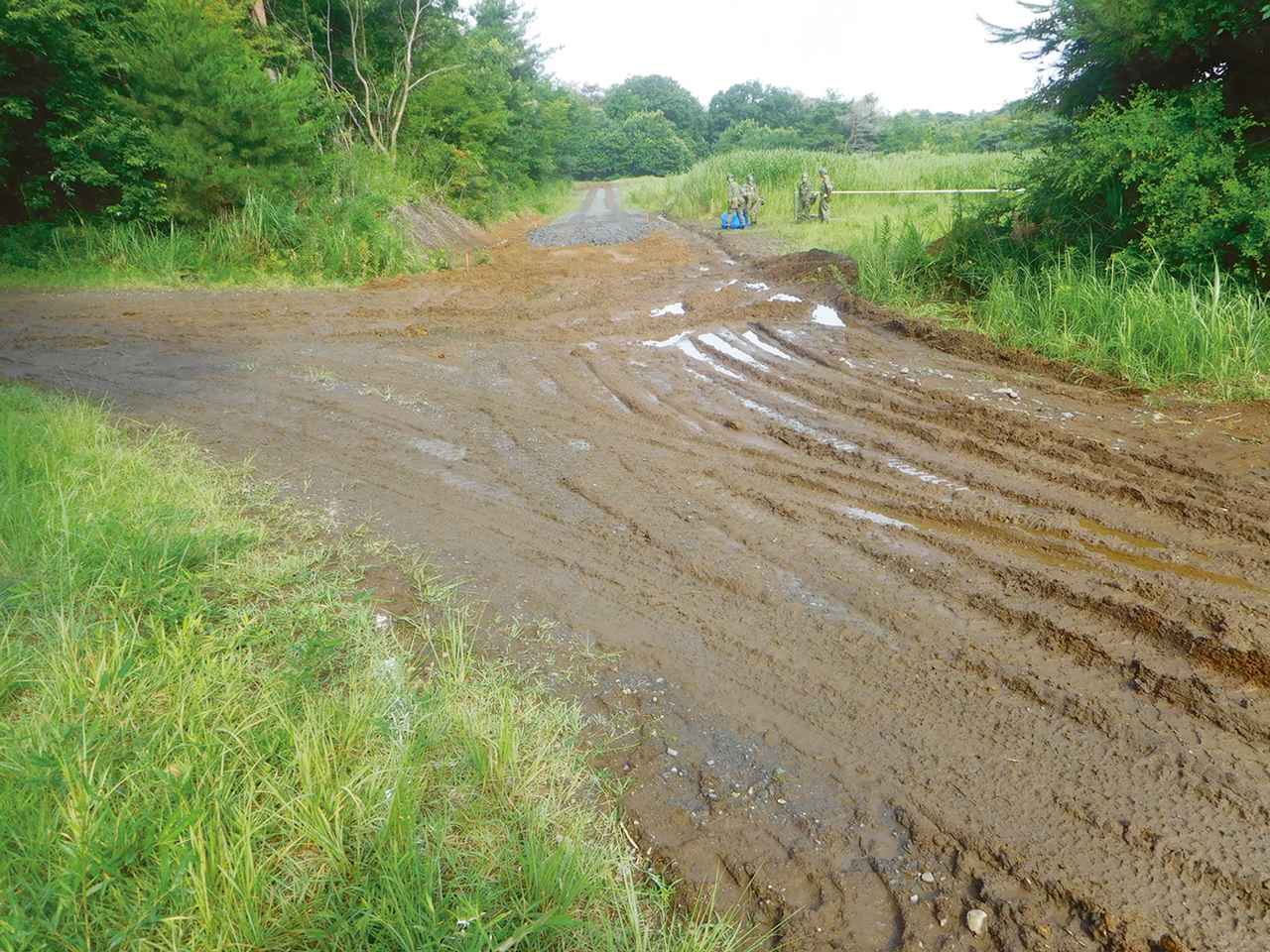 画像: ぬかるみができた荒れた路面。車両がスムーズに移動できるよう重機類を使い道路を作っていく