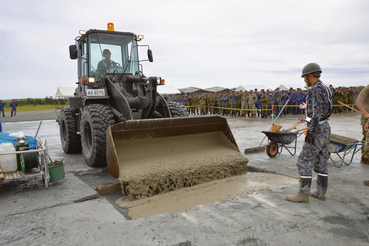 画像: 形を整えた弾痕内に早強コンクリートを投入。投入後は隊員たちがならし、コテなどを使い整形する。すぐに固まるので作業は時間との勝負だ