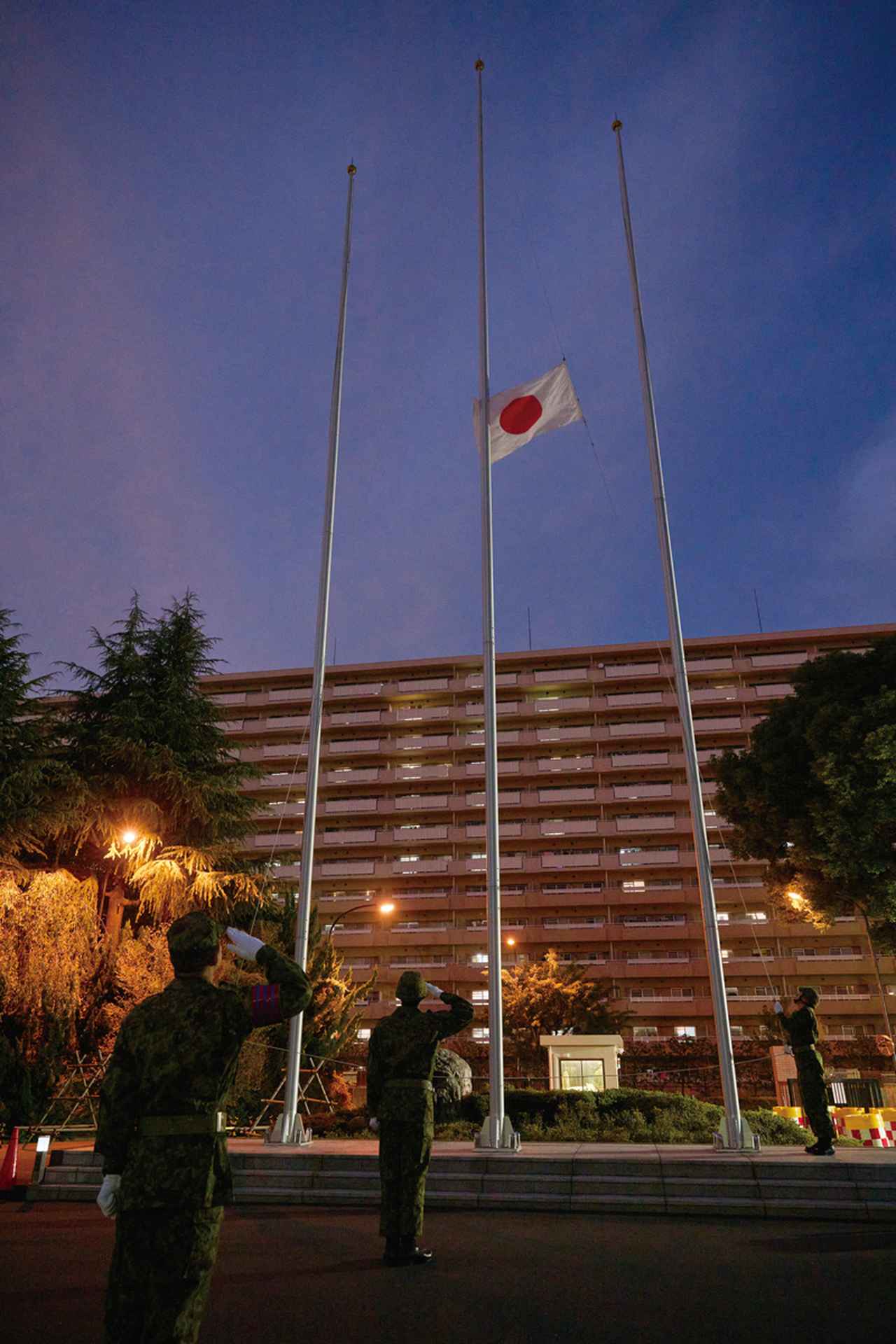 画像: 国旗降下を行う駐屯地当直司令（左下）。5分前に降下を担当する隊員と事前に予行を行い、本番3分前には待機している