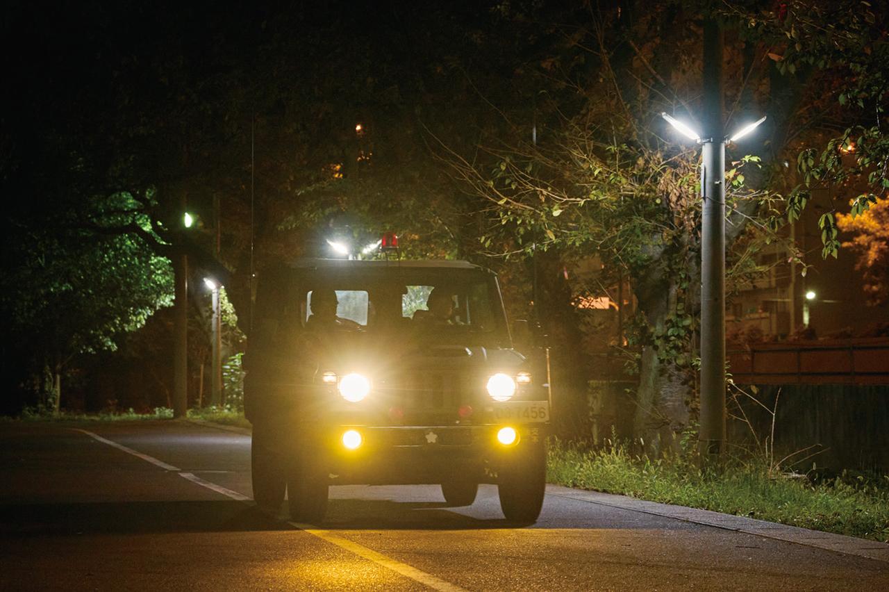 画像: 車両で巡回する駐屯地当直司令と警衛。外柵沿いをはじめ主要地点を丁寧に見回り、異常の兆しや不審者の侵入がないかを確認していく。静まり返った夜間でも目を光らせている