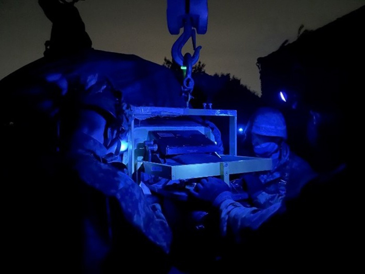 画像: 暗闇の中ヘリコプターの整備を行う隊員。夜間は工具などを紛失するリスクが高まる