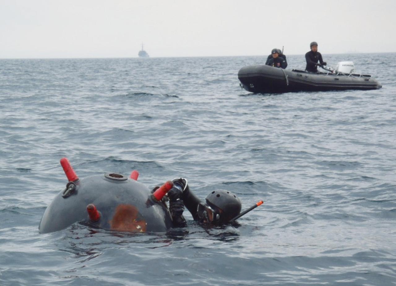 画像: 浮遊機雷を用いた爆発物処理訓練を行うEOD員（水中処分員）。高度な潜水技術と海の爆発物「機雷」に対しての幅広い知識がもとめられる任務だ