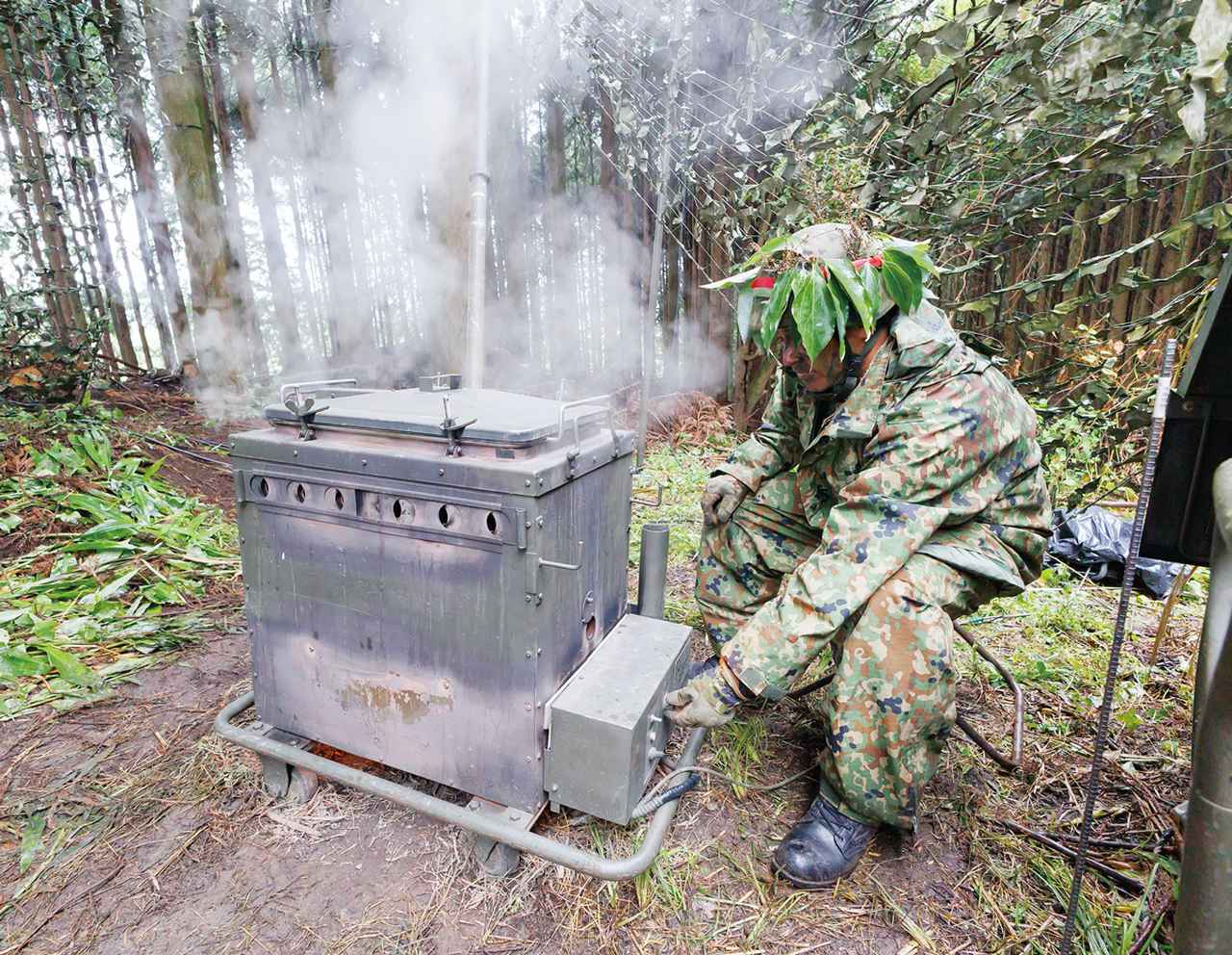 画像: ⑤野外炊具1号で戦闘糧食を加熱:分離して使用できる野外炊具1号で戦闘糧食を加熱する炊事班の隊員