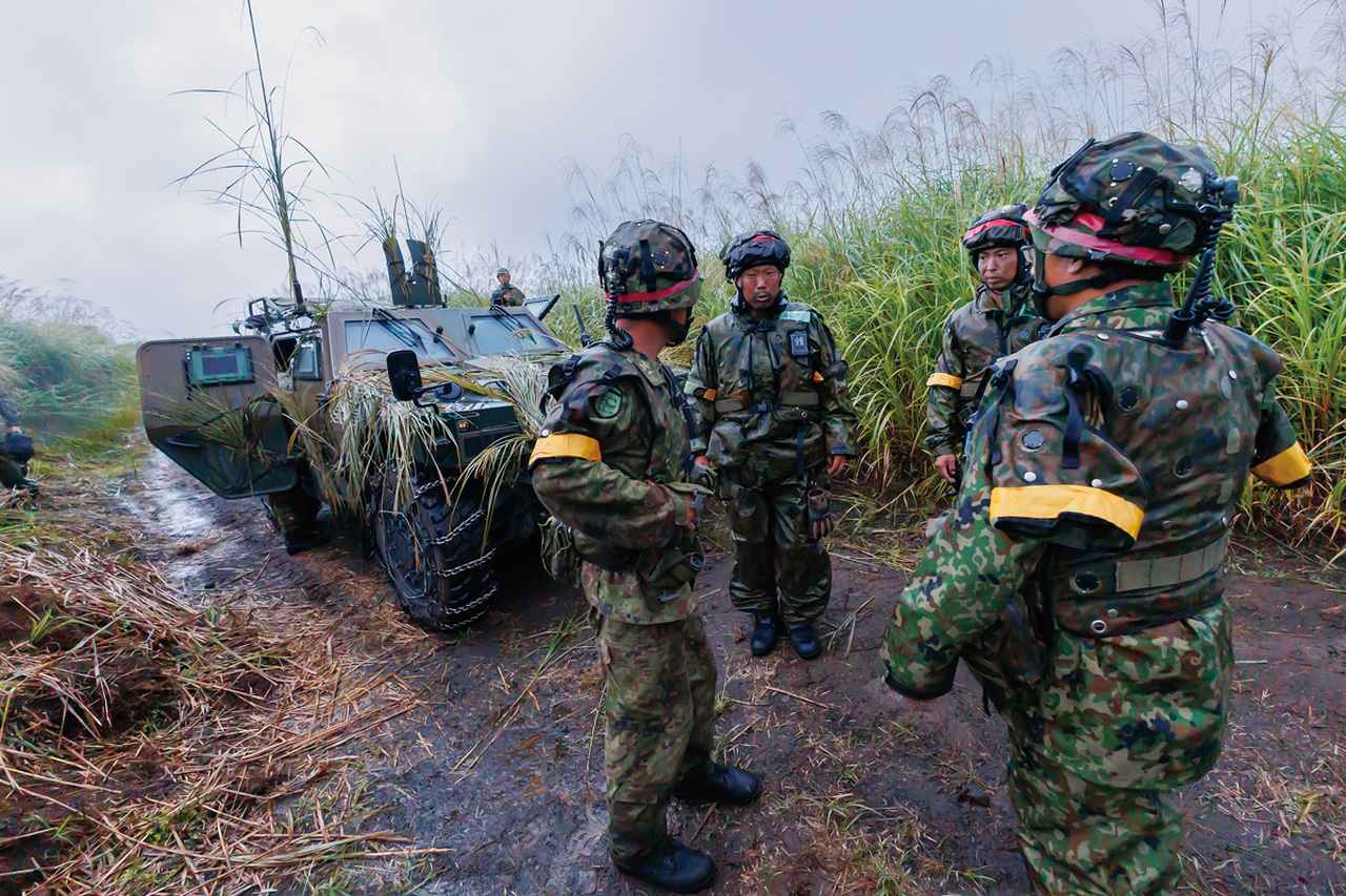 画像: ⑦後退後に事後戦闘に関わる情報交換を実施：敵に前線を突破され、後退した地点で今後の戦闘について情報交換を行う35普連の警戒部隊の隊員たち