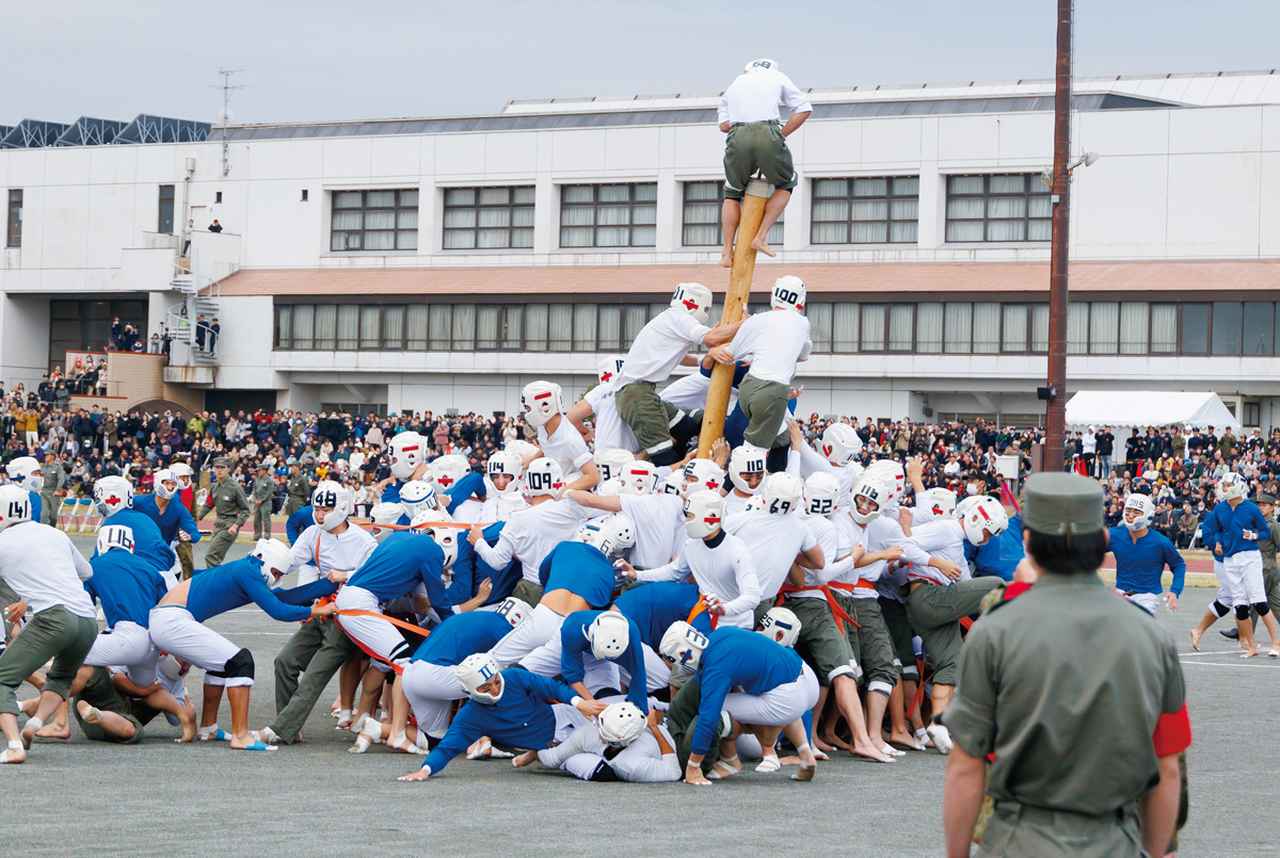 画像: 「棒倒し」の決勝戦。棒を倒されまいと周囲を固めて必死に守る防御陣と、その隙を狙ってどうにか棒を傾けたいと飛びかかる攻撃陣