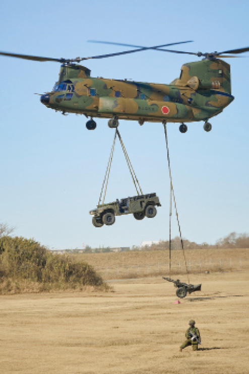 画像: 作戦を支援する装備品の降下。車両や火砲などの重量装備品をCH-47JAにつり下げ前線に輸送。地上で隊員が待機し、つり下げ用のフックを外して装備品の点検や設営などを行う