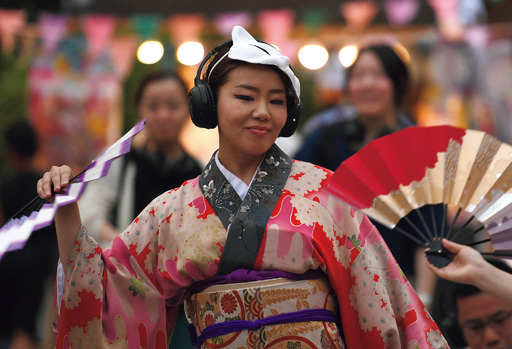 画像: ヘッドホンを付け踊る祭り参加者。「踊りに没入できる」という高評価の声も挙がっている（写真提供／AFPBB）　※写真は以前のもの