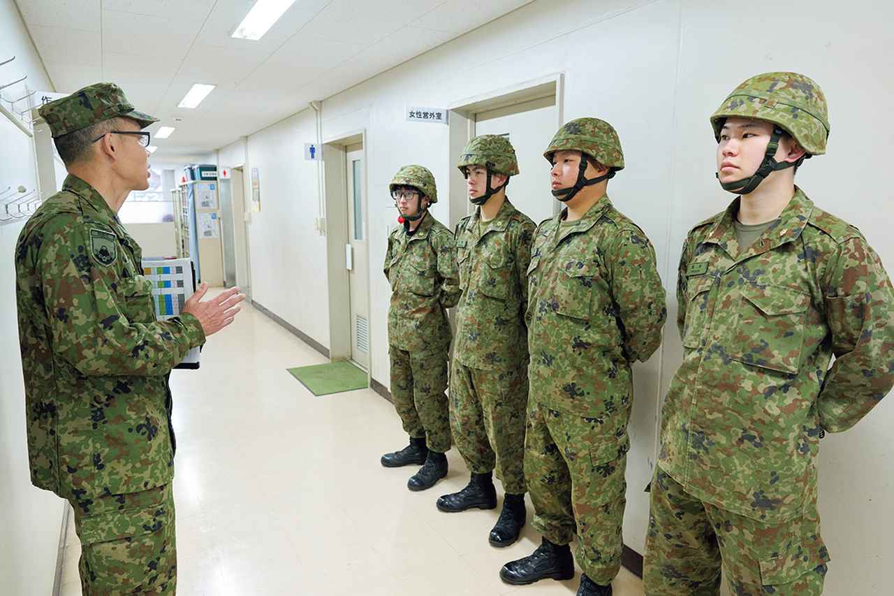画像: 【筆記試験の前に検定の概要を説明】試験会場となる練馬駐屯地に着隊した受検者たちは、荷物の整理を終えた後、廊下に並び、教官から伝えられる検定の注意事項について耳を傾けた