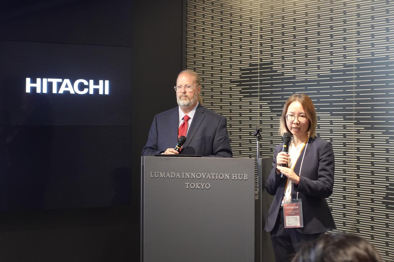 画像: Lumada Business Awardで表彰されるモンロー氏とヤン氏。授賞式でモンロー氏は「一社単独では成し得ない課題解決に“One Hitachi”で挑戦できたことをうれしく思います。その挑戦が評価され、今回の受賞に至ったことを誇りに思います」とコメント。ヤン氏も「研究開発部門として、日立のビジネスに具体的な価値を提供し、その成果が受賞という形で認められたことを大変光栄に感じています」とコメントして喜びを示した