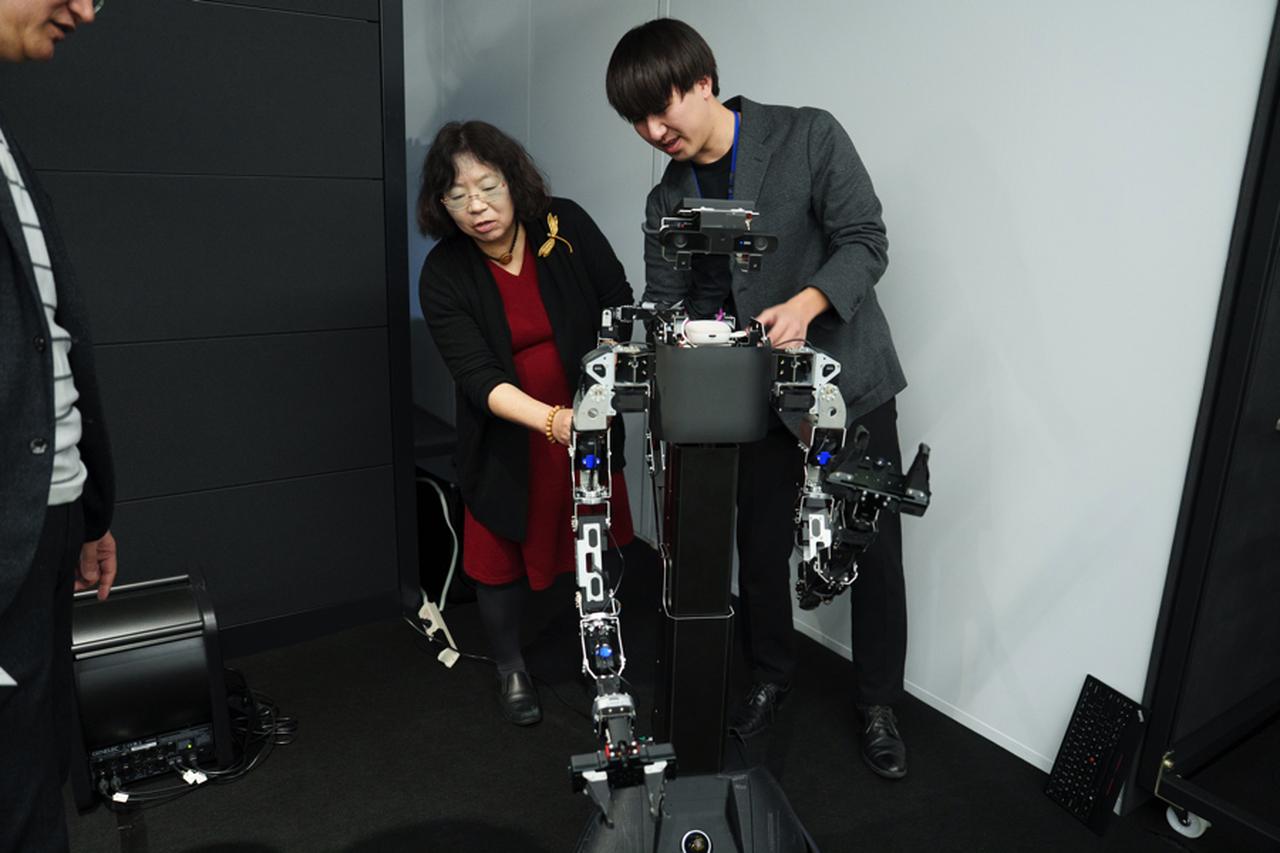 画像: NaivyのデモンストレーションでフィジカルAIを体験する今井さん。さまざまな疑問を研究者に問いかけていた