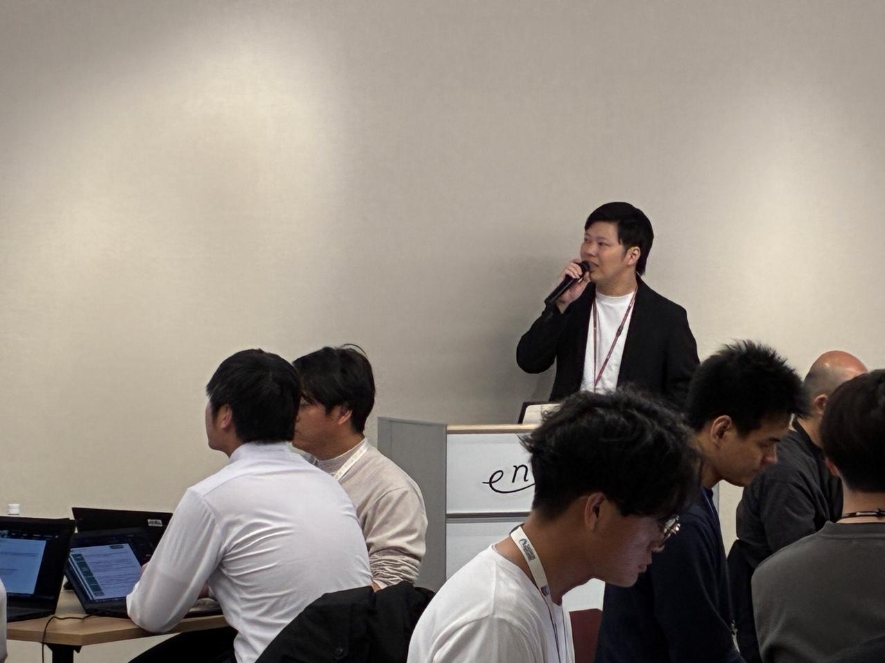 画像: 各部門から選出されたチャンピオンが一堂に会した第1回ネットワーク会の様子。進行を務める吉松さん。