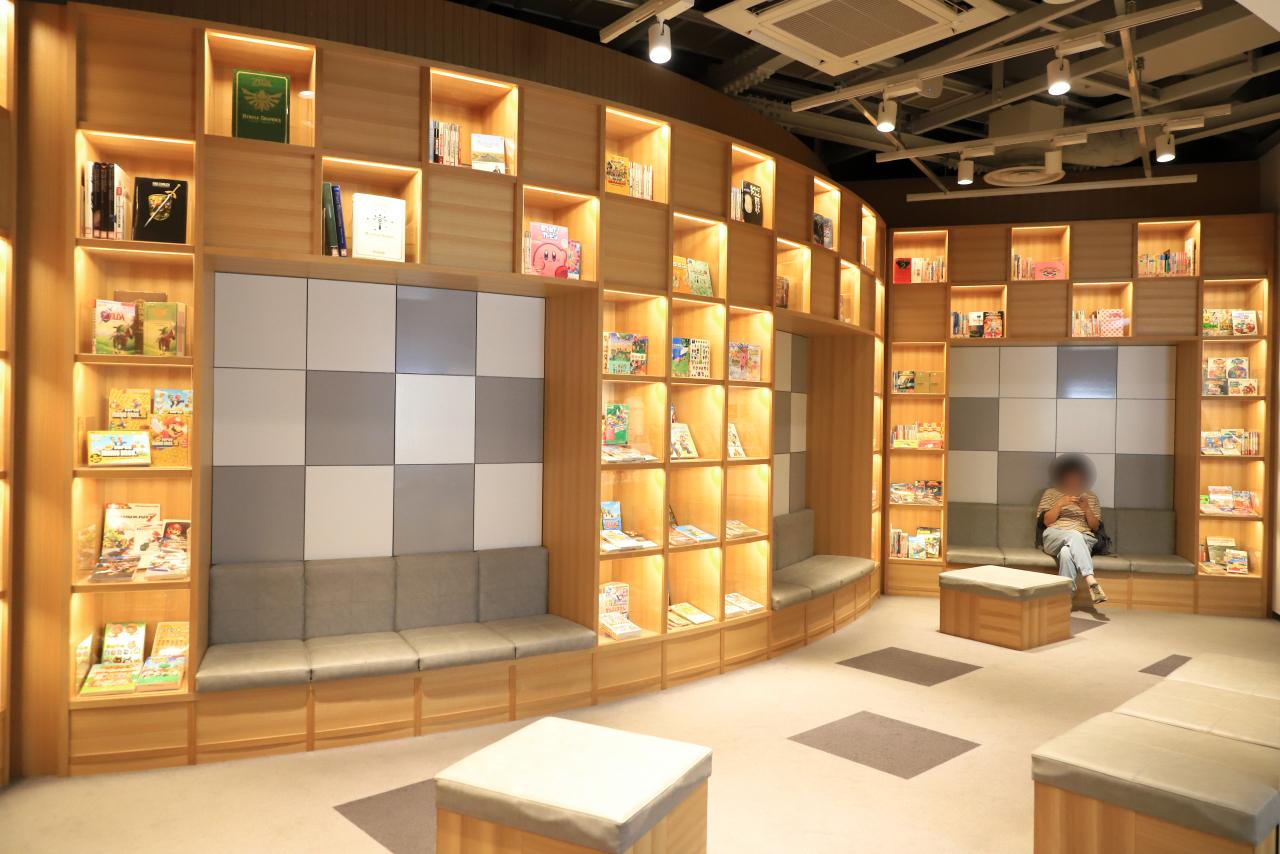 画像: 花札ワークショップ予約カウンター(第1展示棟 1階ロビーのインフォメーションカウンター)そばには、休憩スペースあり。歴代任天堂作品の攻略本が展示されています。