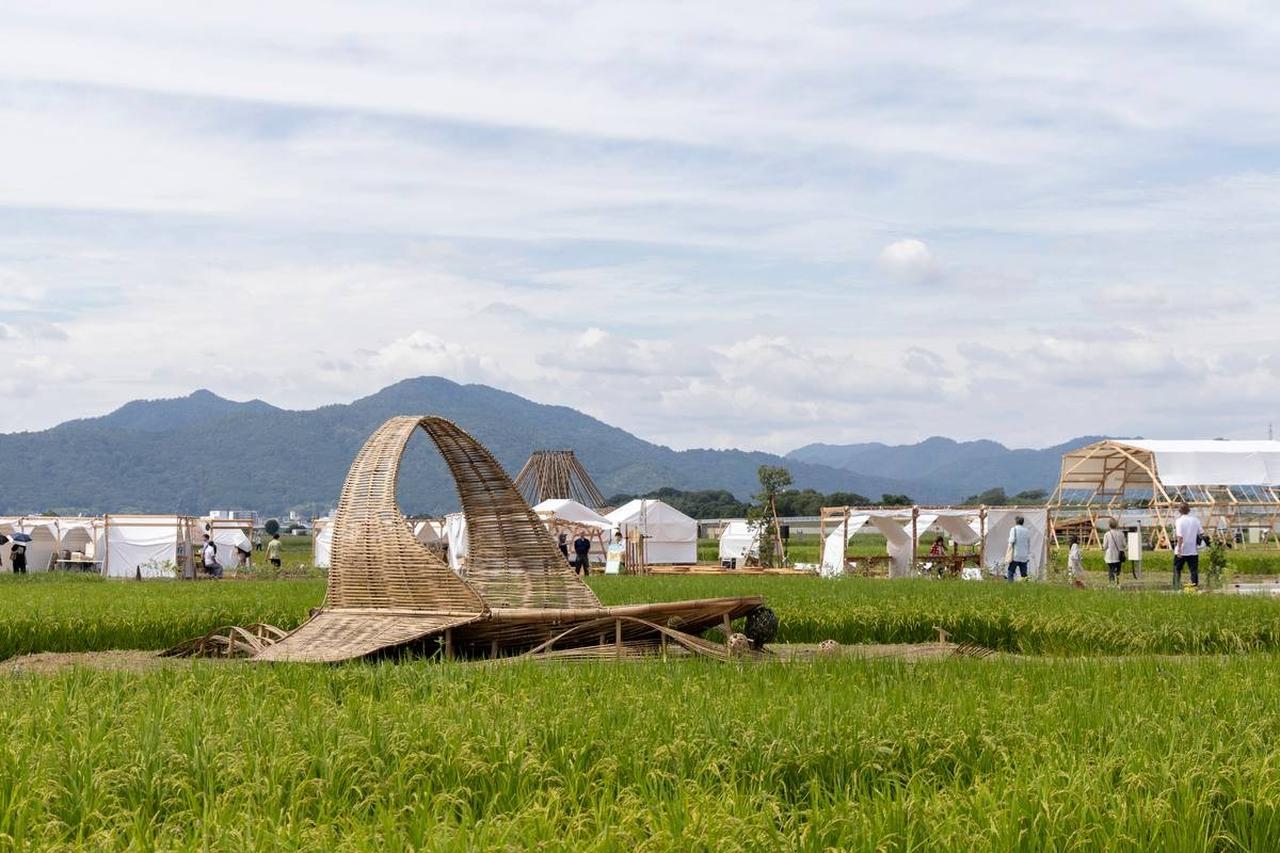 画像: 山並みを背景に、田んぼや園路のあいだにアート作品や休憩所が点在する亀岡会場。広い空の下、のびやかな田園風景を眺めながら散策できる