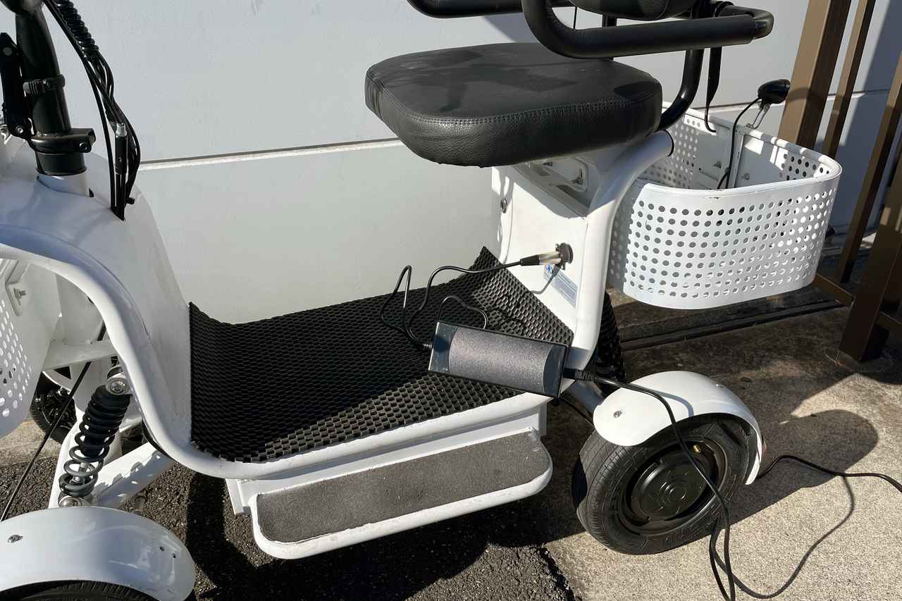 画像: 足元は積載スペースで標準装備のショッピングバッグなどが置けます。プラグイン充電はシート下のソケットにプラグを差し込んで行います。 ※市販車両では、本体下部のバッテリーボックス側に変更される予定です。