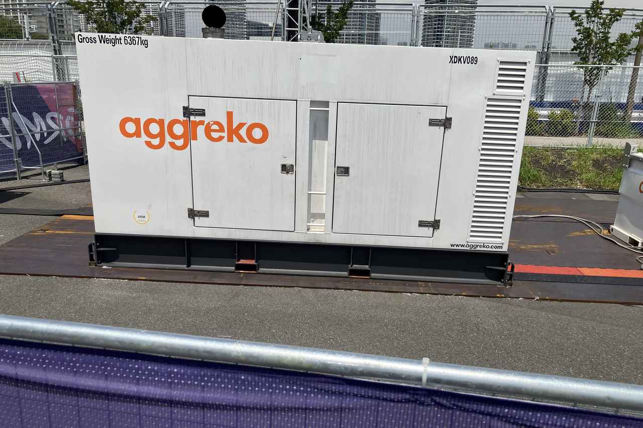 画像: 会場裏手に設置されたAggreko社の巨大な仮設発電機。従来の軽油に代わりHVO（水素化植物油）燃料を使用することで、CO2排出量を最大90%削減しつつ、ナイトレースの膨大な電力を安定供給する。