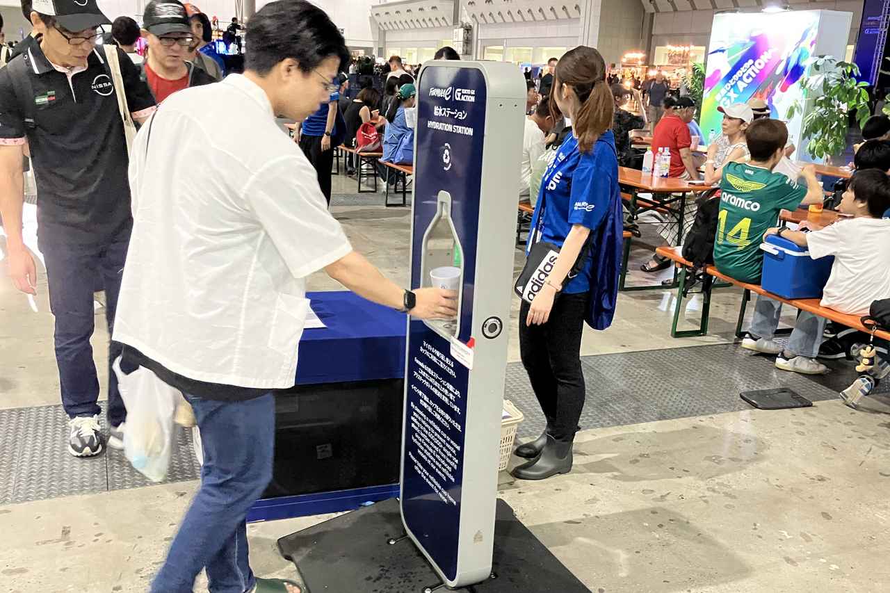 画像: 屋内のファンビレッジに設置された給水ステーション（Hydration Station）。猛暑のなか来場者のオアシスとして機能し、無料配布のエコカップへの給水を通じてサスティナブルなイベント運営と熱中症対策を両立させている。