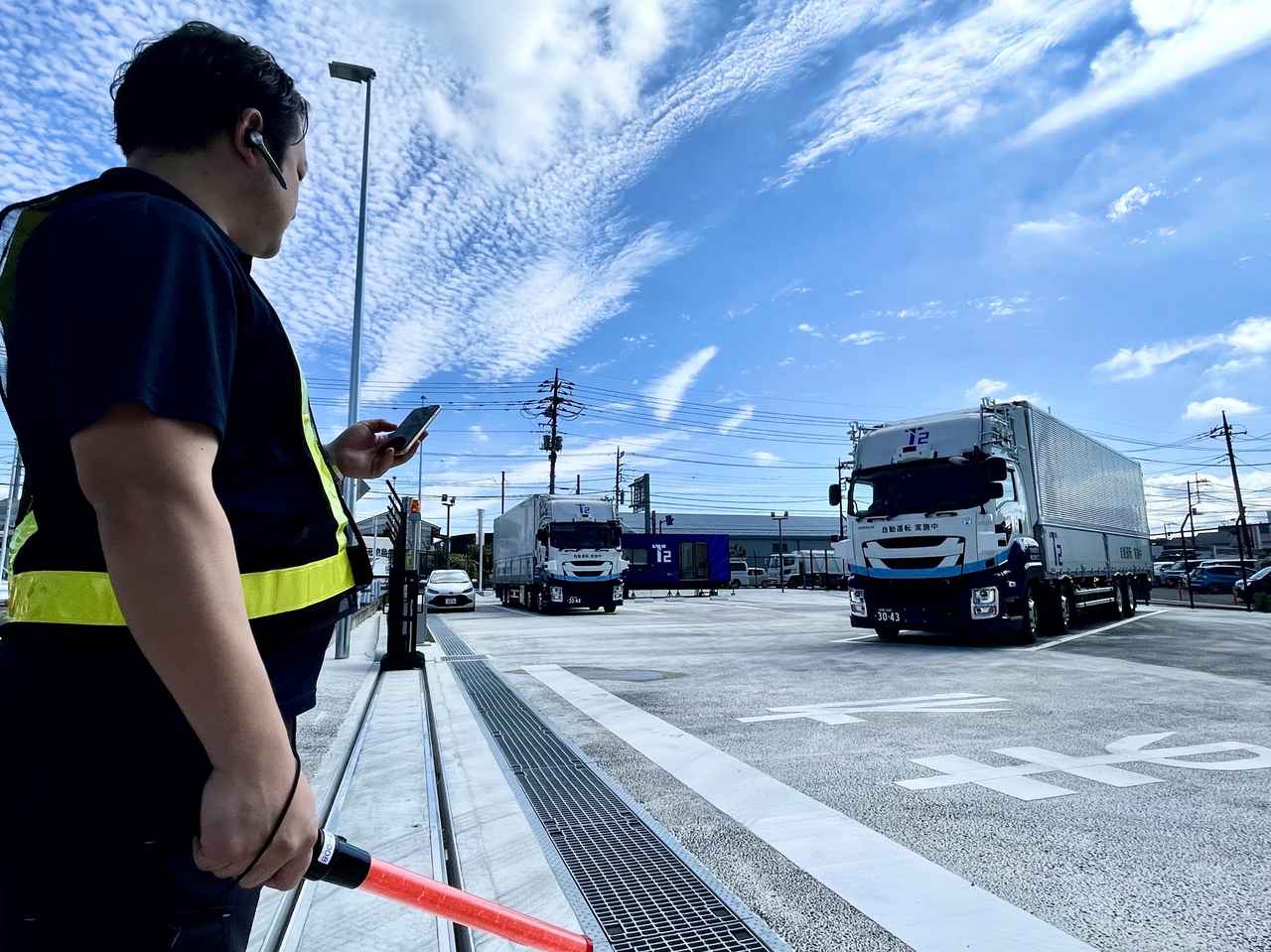 画像: 切替拠点からの出発にあたり作業員がスマートフォンから自動運転トラックに発車を指示する様子。