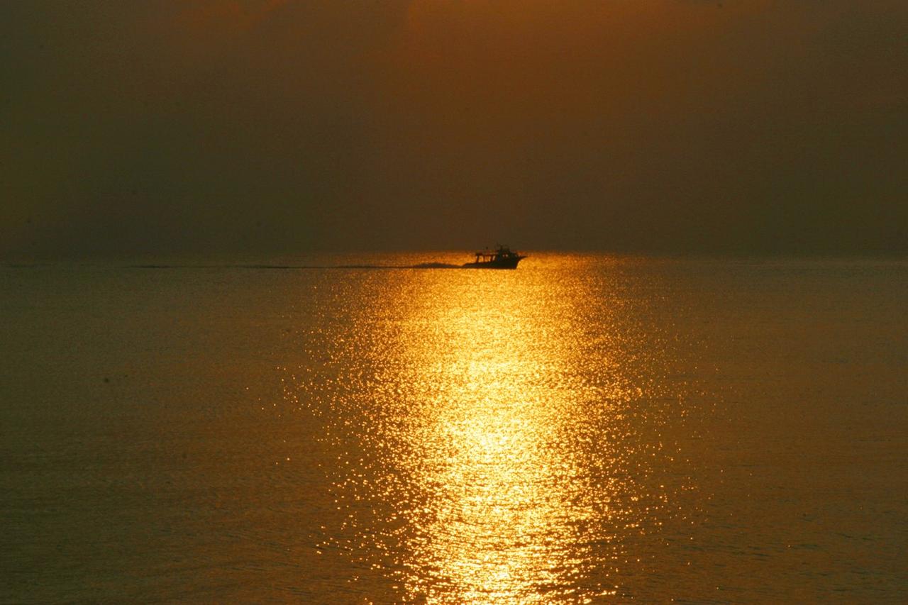 画像: 夕陽の中を進むボートはどこの港に向かっているのだろうか