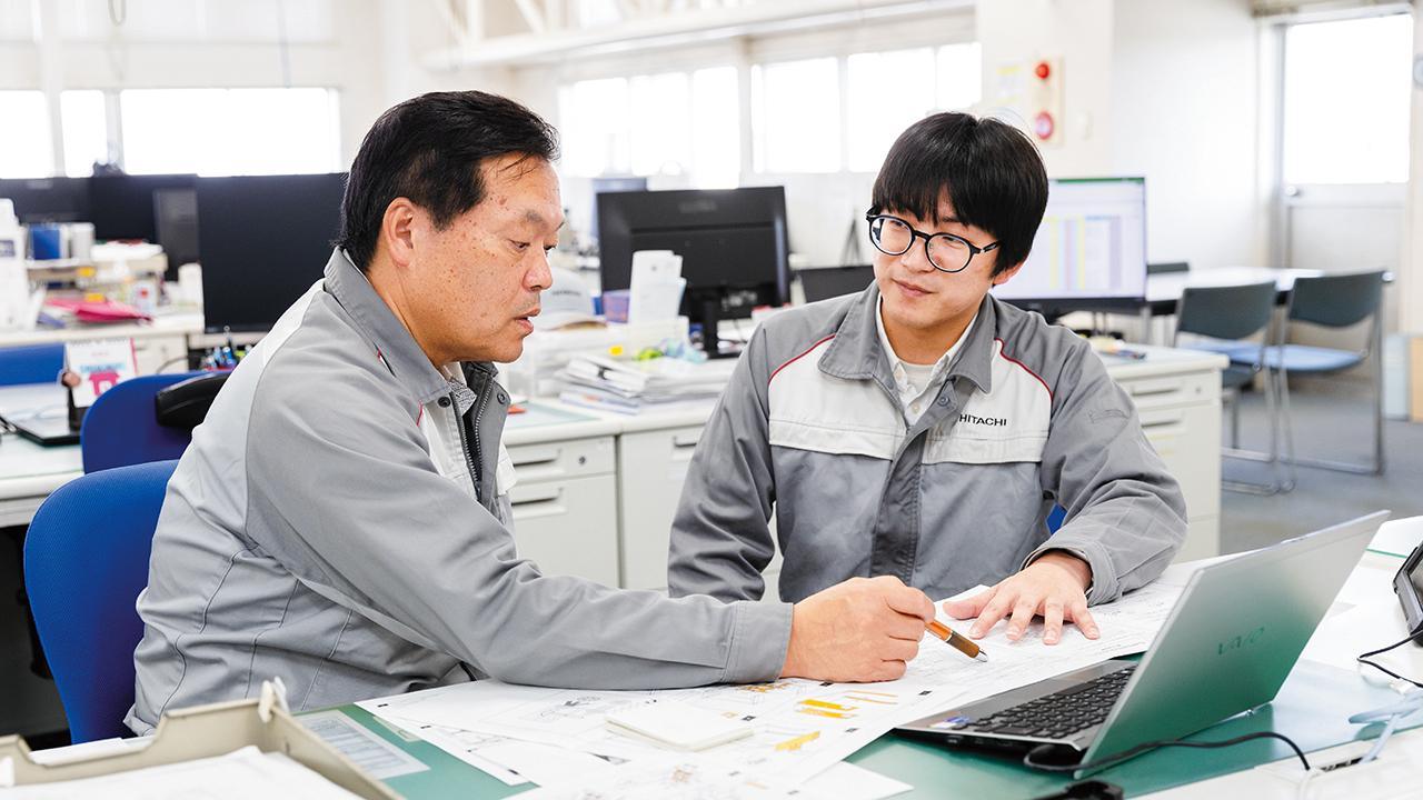 画像: 製造技術係のオフィスで佐藤(右)と打ち合わせを行う