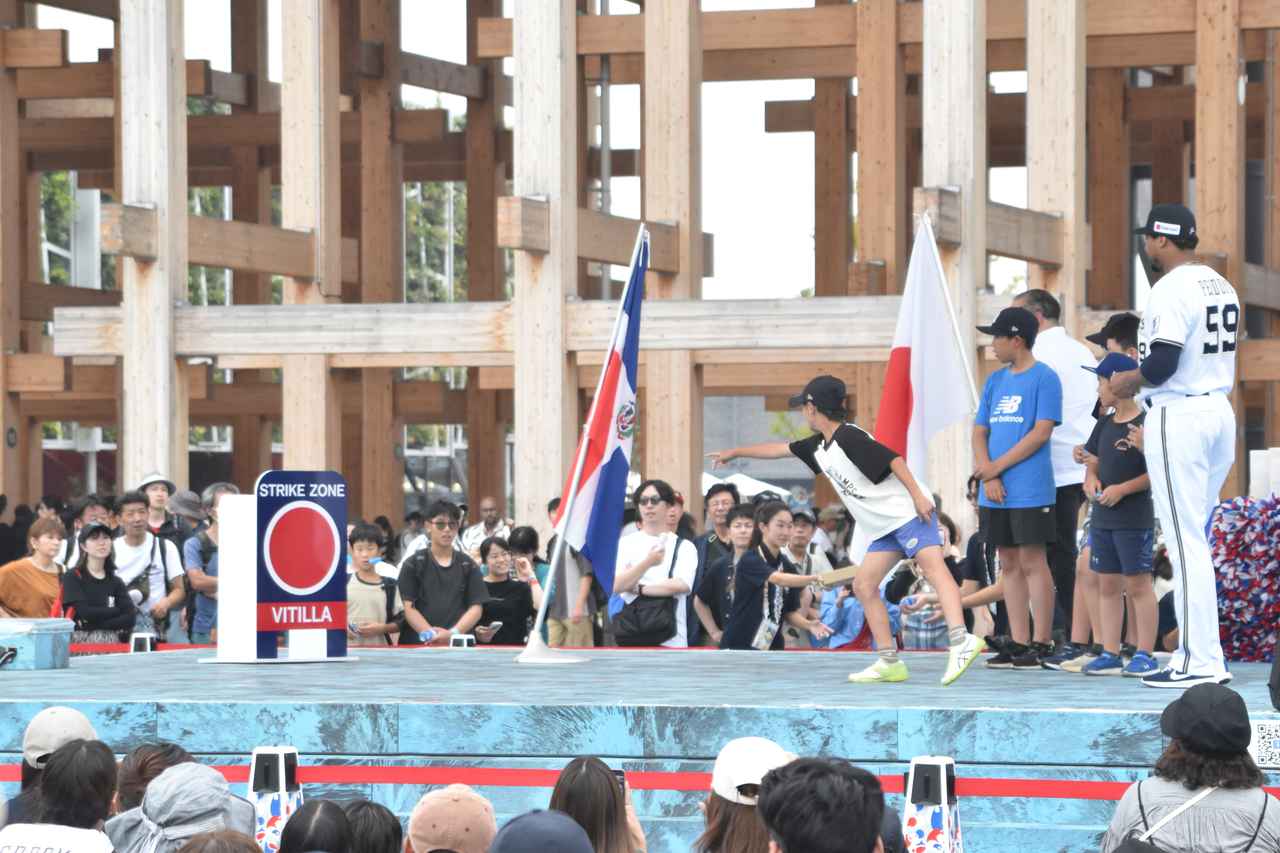 画像: ペットボトルのキャップを、赤丸のストライクゾーンに入れようと奮闘する子供たちと、その挑戦を見守るペルドモ投手。