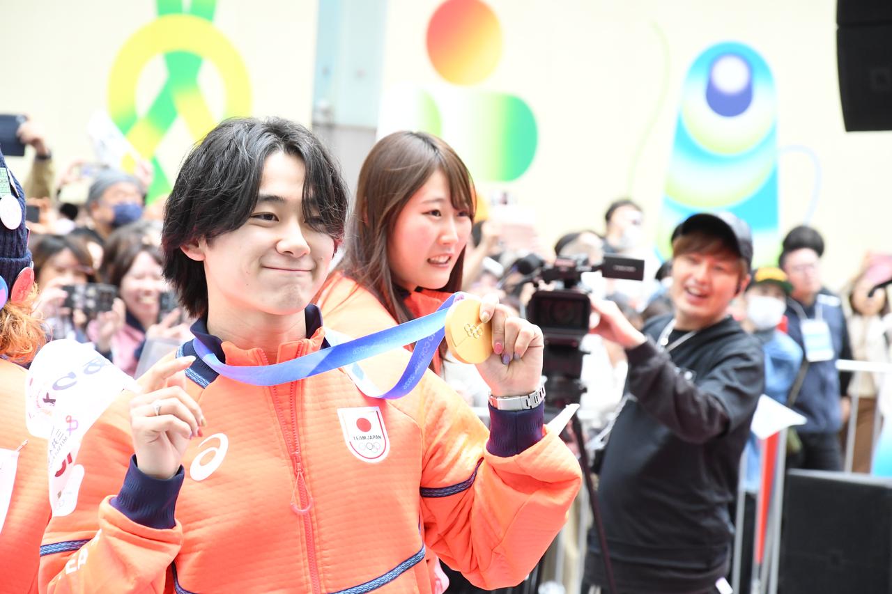 画像: 金メダルを掲げて、写真撮影のリクエストに応じる戸塚優斗選手（左）。パレード後の会見で「応援の声を実際に聞けて、こちらから感謝の意を込めてあいさつできてうれしかった。声援を滑りに変えて、五輪や今後の大会に全力で挑みたい」と思いを明かした。