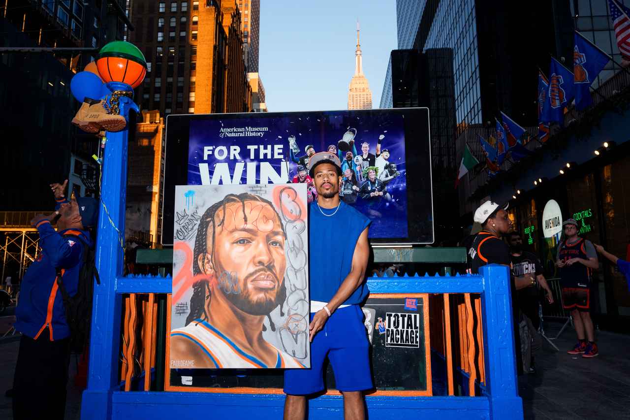 画像: NBAファイナル第1戦を前に、地下鉄もニックス色となり盛り上がるニューヨークの街。写真はジェイレン・ブランソンの絵とともに立つアーティストのポール・ジョンソンさん　Photo by Adam Gray/Getty Images